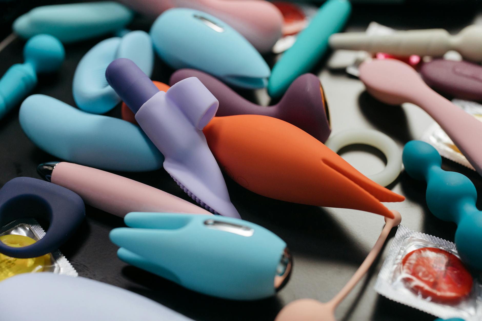 A blue silicone clitoral vibrator held in hand against a purple background