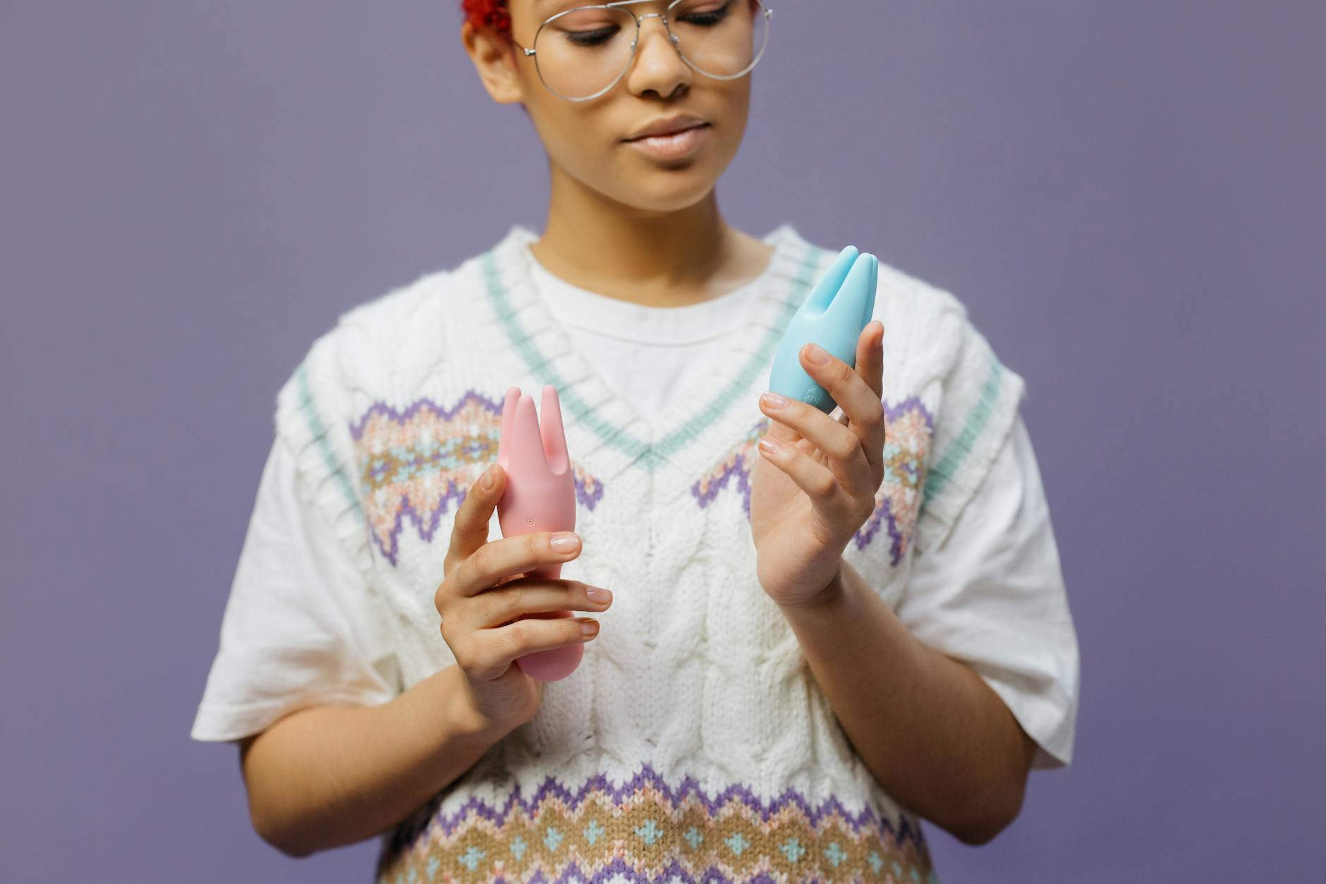 Woman thoughtfully examining a blue silicone clitoral vibrator, symbolizing personal choice and healing